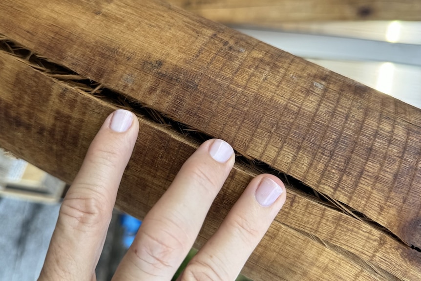 A woman's fingers feel the buried log that was used on the porch of the tiny house