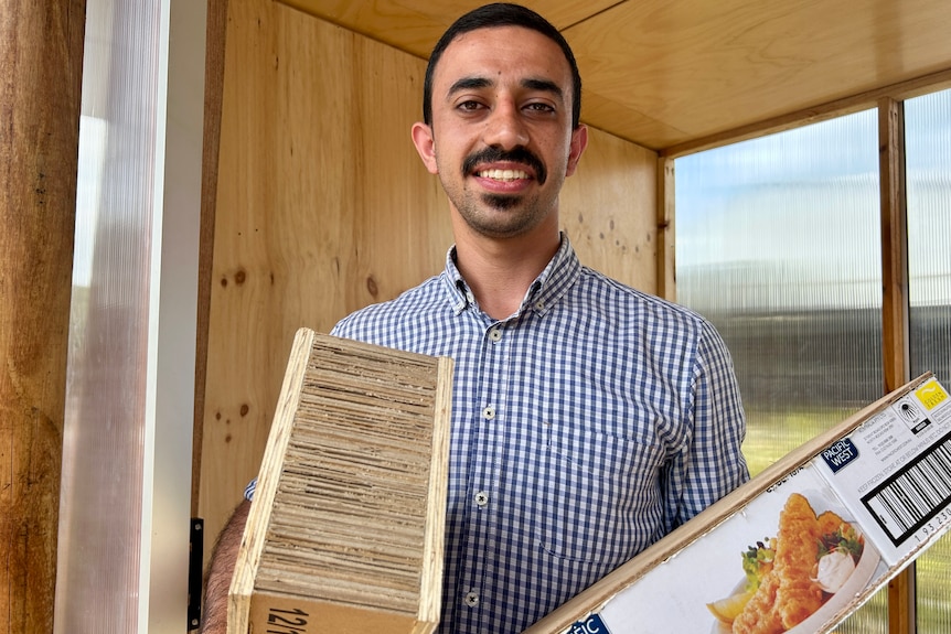 A man holds two pieces of compressed cardboard