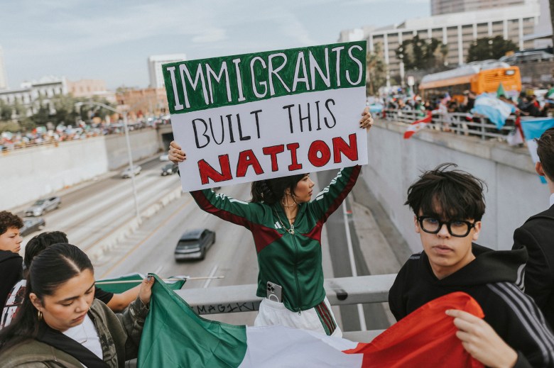 A person in a green training suit holds a sign with the inscription 