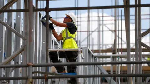 Reuters a male construction worker on a building site and wears a protective helmet and a yellow jacket with high visibility