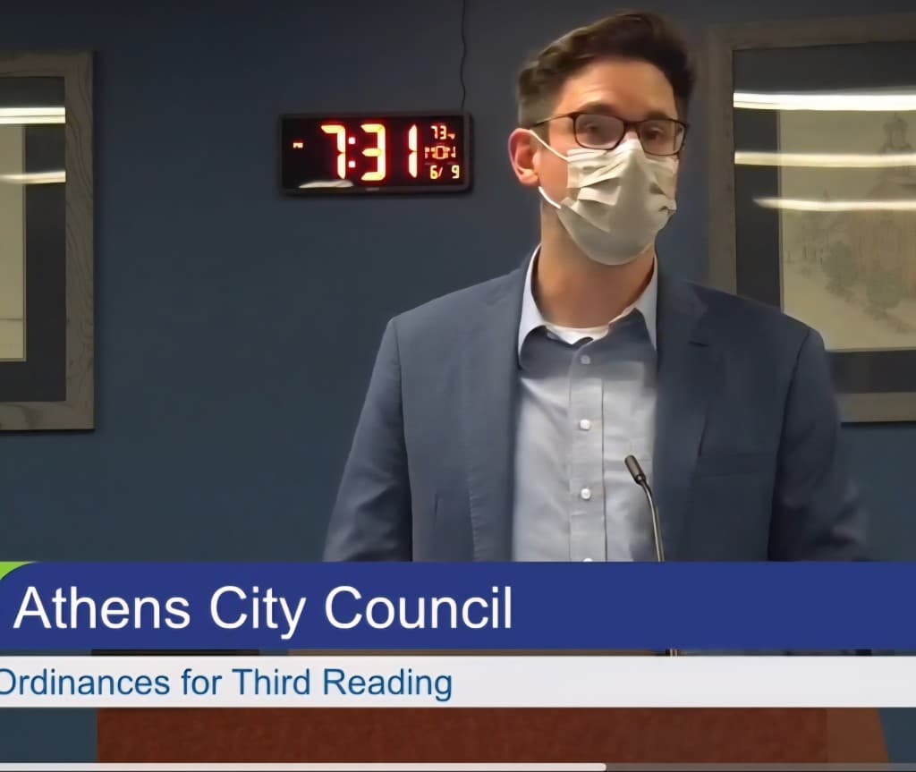 Man in the mask speaks before a podium