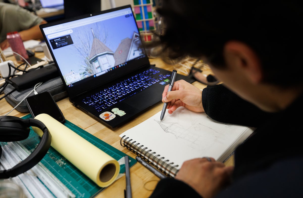A student outlines a building in a notepad.