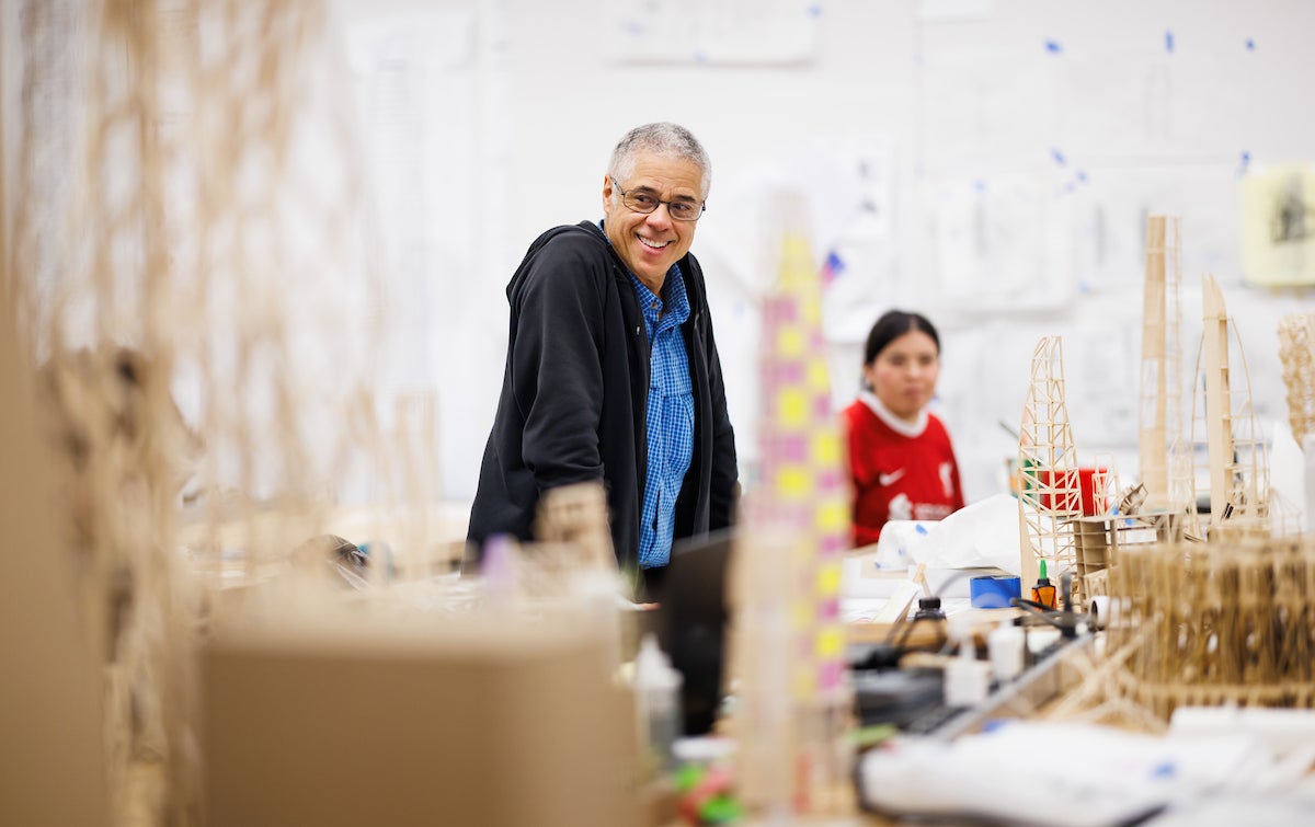 A professor stands and looks around in wooden scale models of skyscrapers.