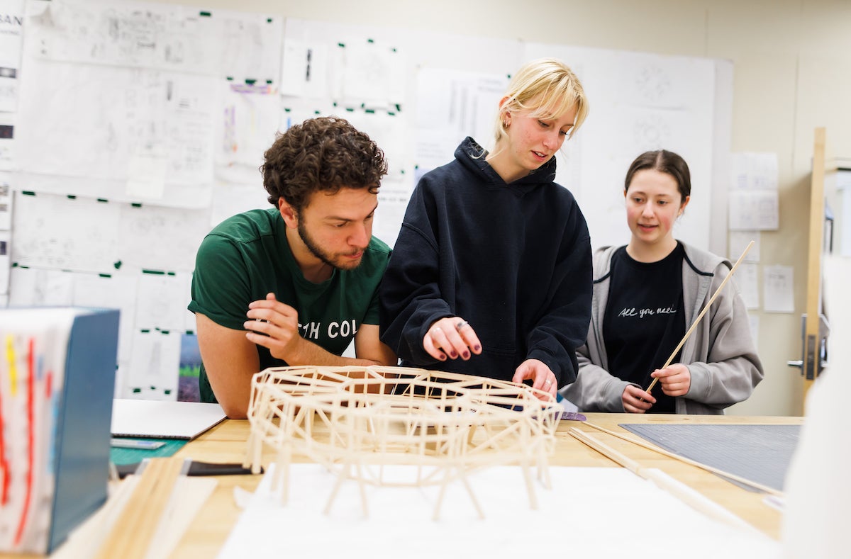 Architecture students put together a wooden model of a skyscraper.