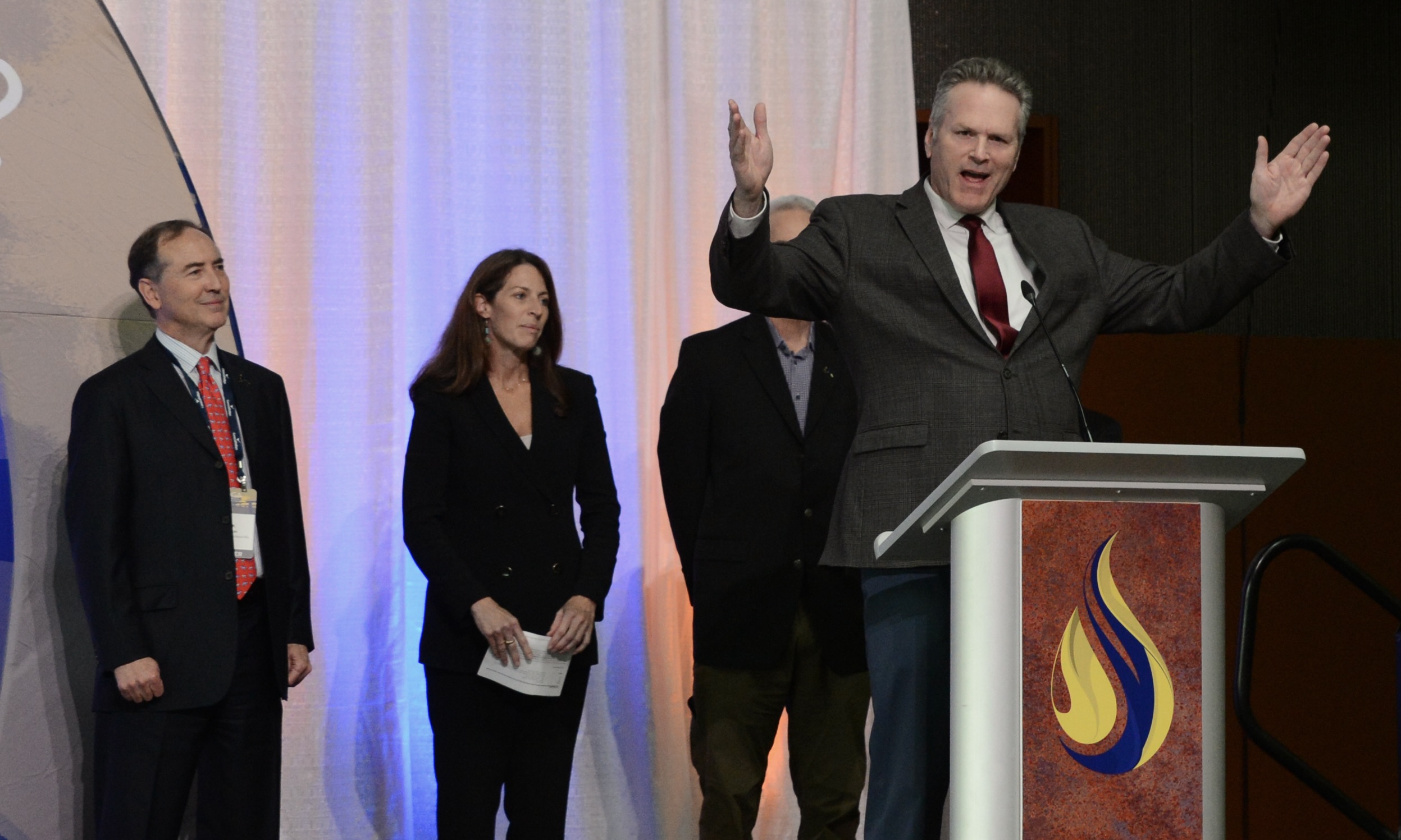 The Alaska Governor Mike Dunleavy talks about his support for the proposed trans-alaska earth gas pipeline on Thursday, August 28, 2025, while Alaska Oil and Gas Association Conference in Anchorage. On the far left is Rex Cannon, co-president of 8 stars LLC, the company that develops the pipeline. (Photo by James Brooks/Alaska Beacon)
