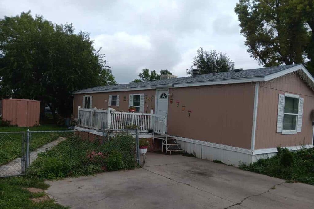 Peach -colored mobile home with fence in front