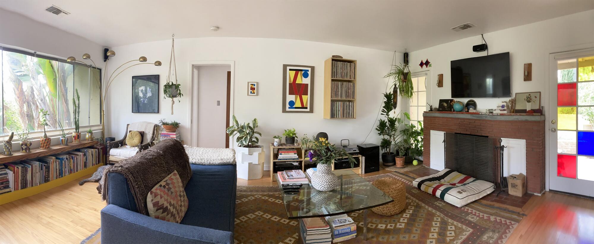 A living room with a red brick fireplace and colorful artwork. 