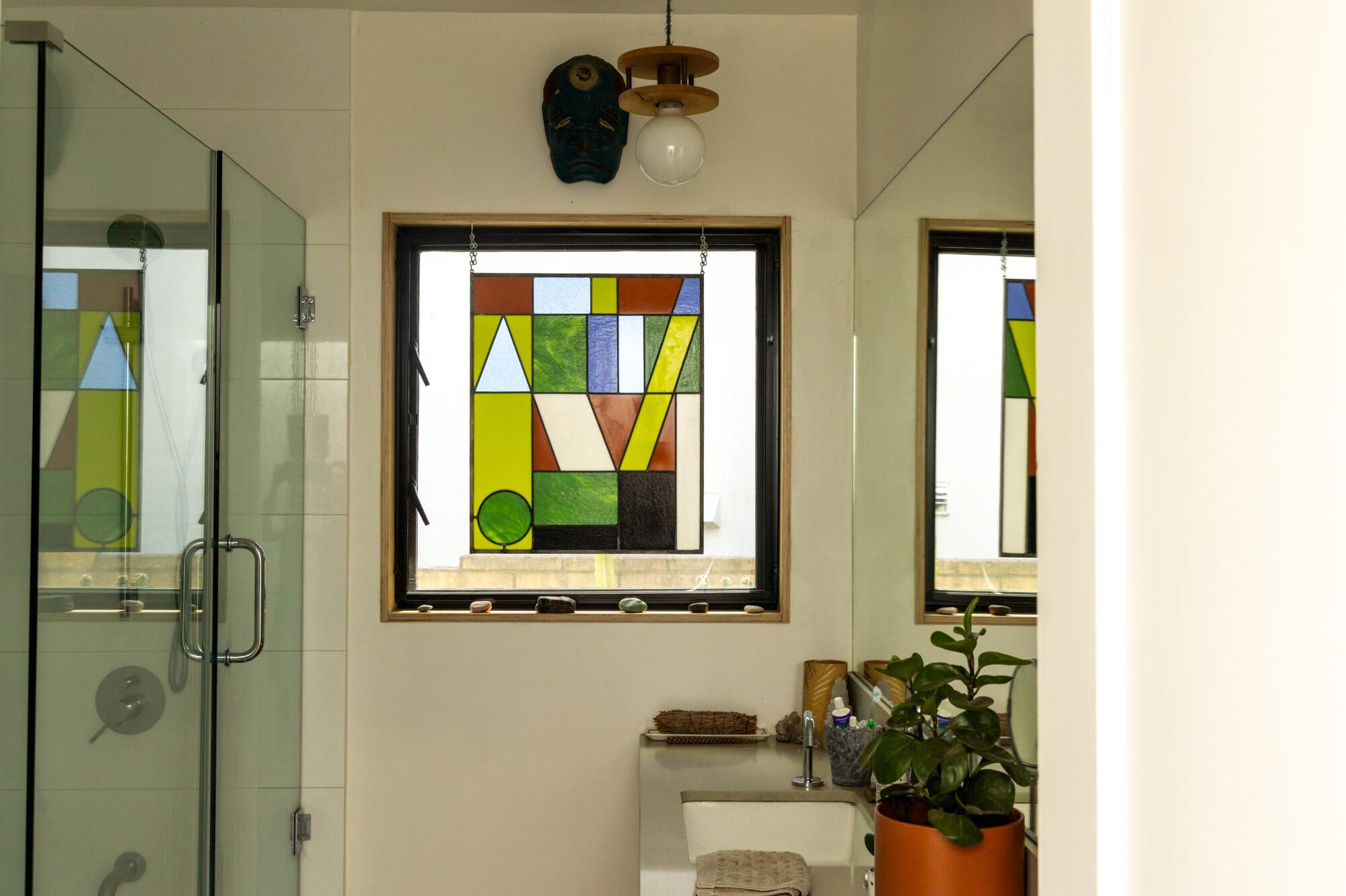 A stained glass panel hangs in the bathroom.