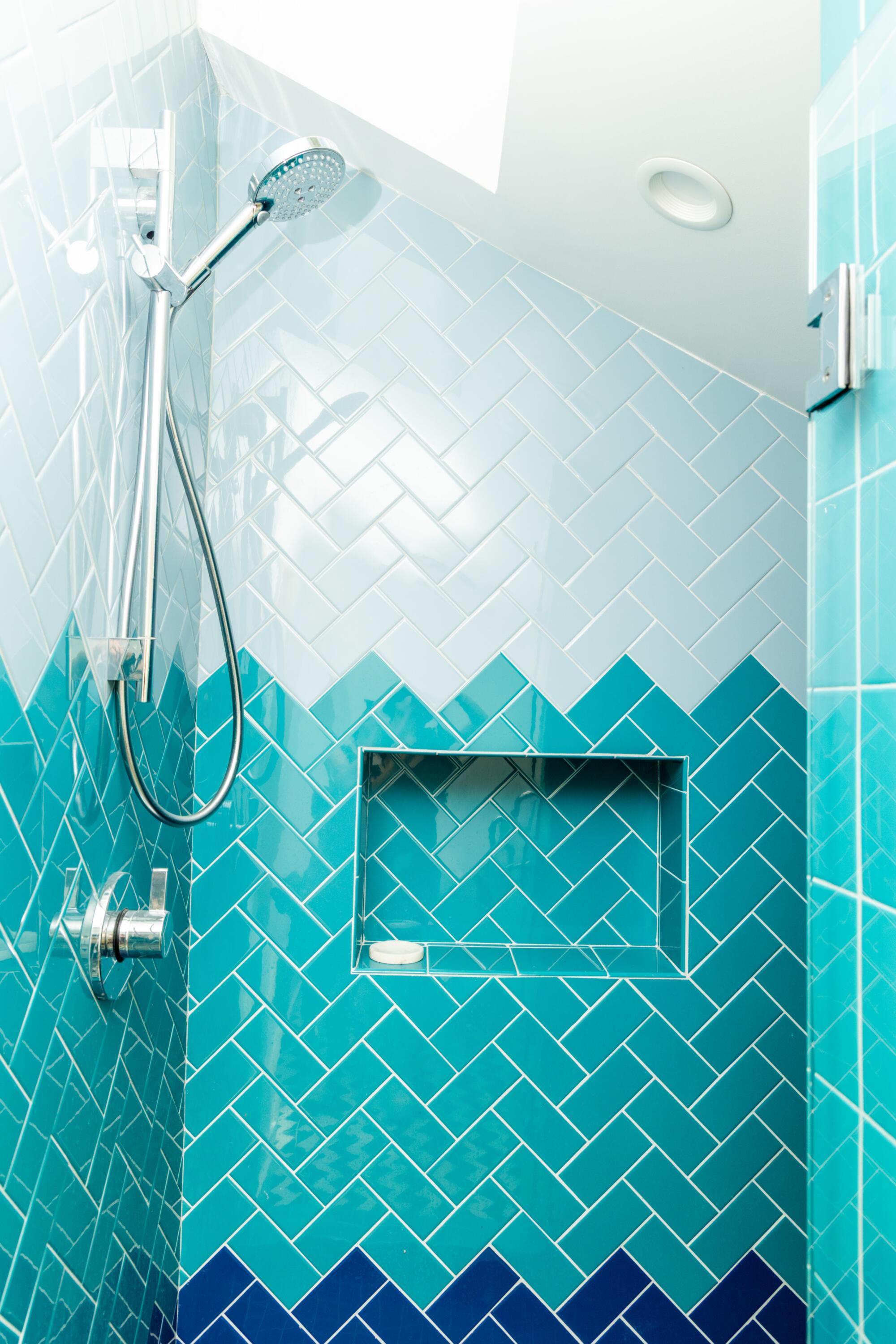 Tiles in different shades of blue in a shower with a high ceiling.