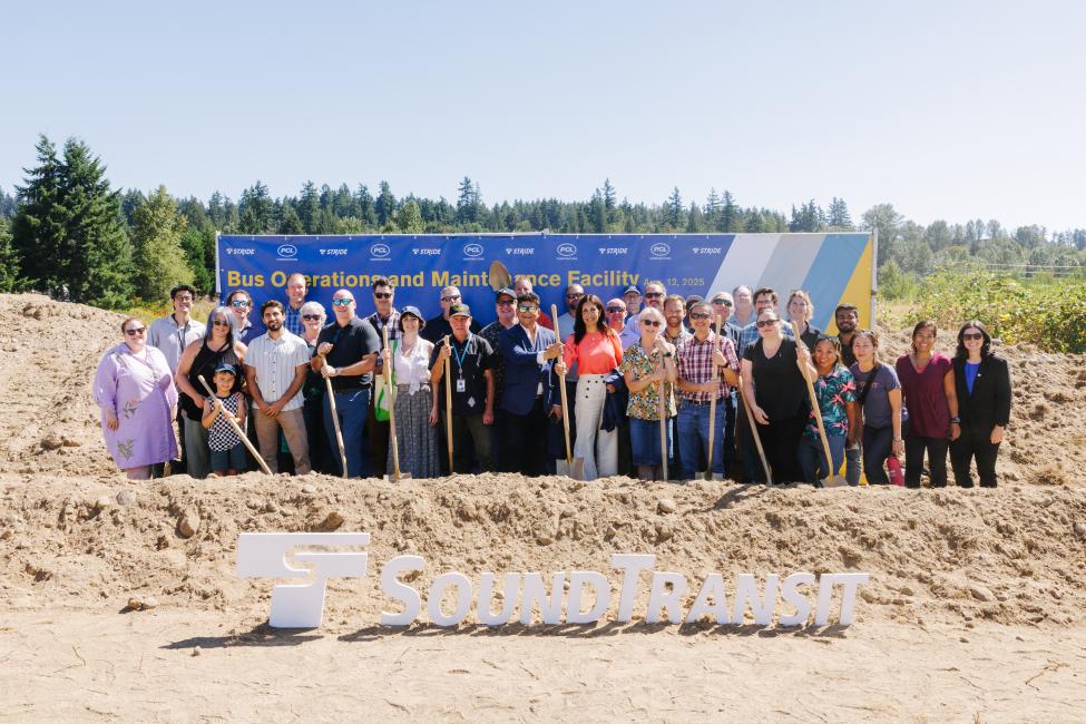 A group of about 30 people pose with golden shovels at the groundbreaking ceremony for a new bus station